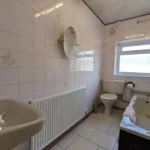 Bathroom with tiled walls, a sink, radiator, toilet, bathtub, wall mirror, and a window letting in natural light. T. Samuel Estate Agents logo is visible in the bottom left corner.